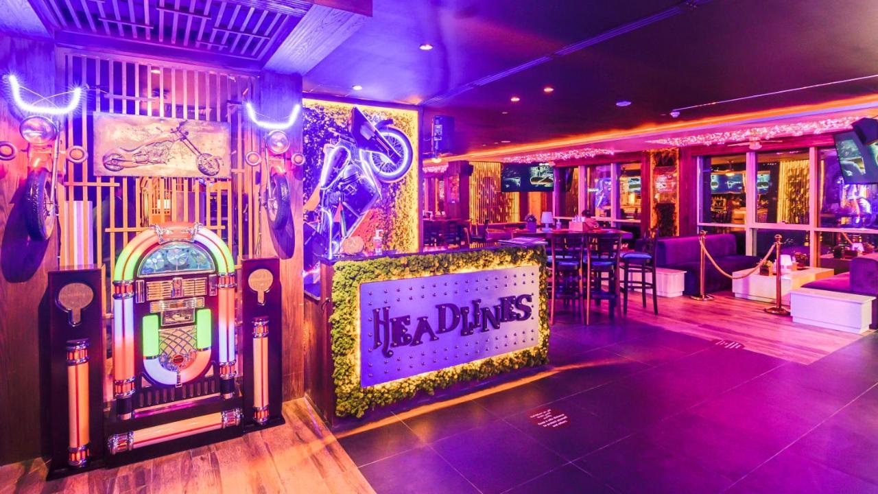 Stella Di Mare Dubai Marina Hotel Esterno foto The photo shows the interior of a vibrant bar or lounge area named "HEADLINES." The design features neon lighting that creates a lively atmosphere. On one side, there is a decorative jukebox, and a motorcycle is prominently displayed as part of the d