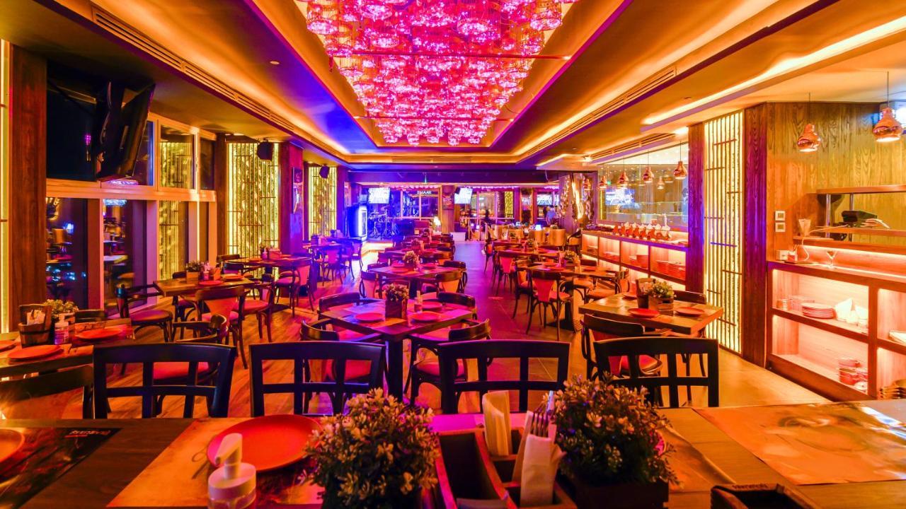 Stella Di Mare Dubai Marina Hotel Esterno foto The photo showcases a vibrant restaurant interior, featuring a lively atmosphere enhanced by colorful lighting. The ceiling is adorned with ornate decorations that emit a warm glow, creating a cozy yet festive ambiance. The dining area is filled with
