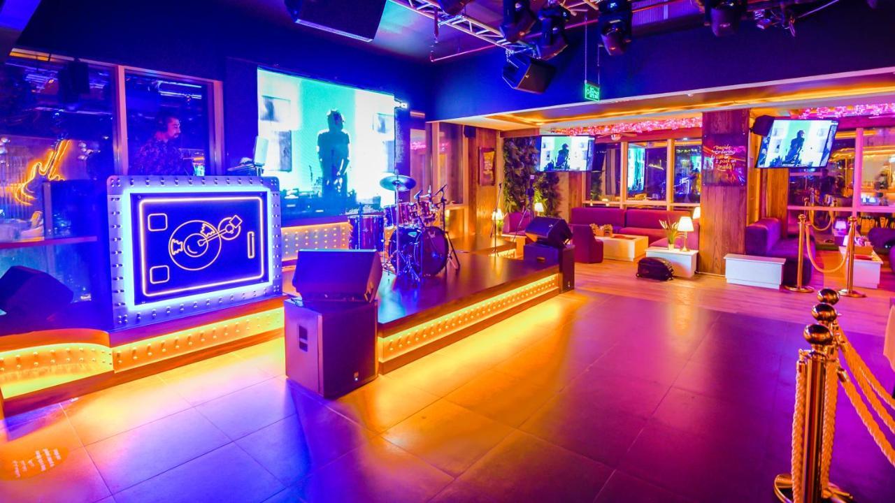 Stella Di Mare Dubai Marina Hotel Esterno foto The photo shows a vibrant and modern entertainment venue, possibly a nightclub or live music space. The area features a stage with a set of drums and a DJ booth illuminated by colorful lights, creating an energetic atmosphere. Various screens display