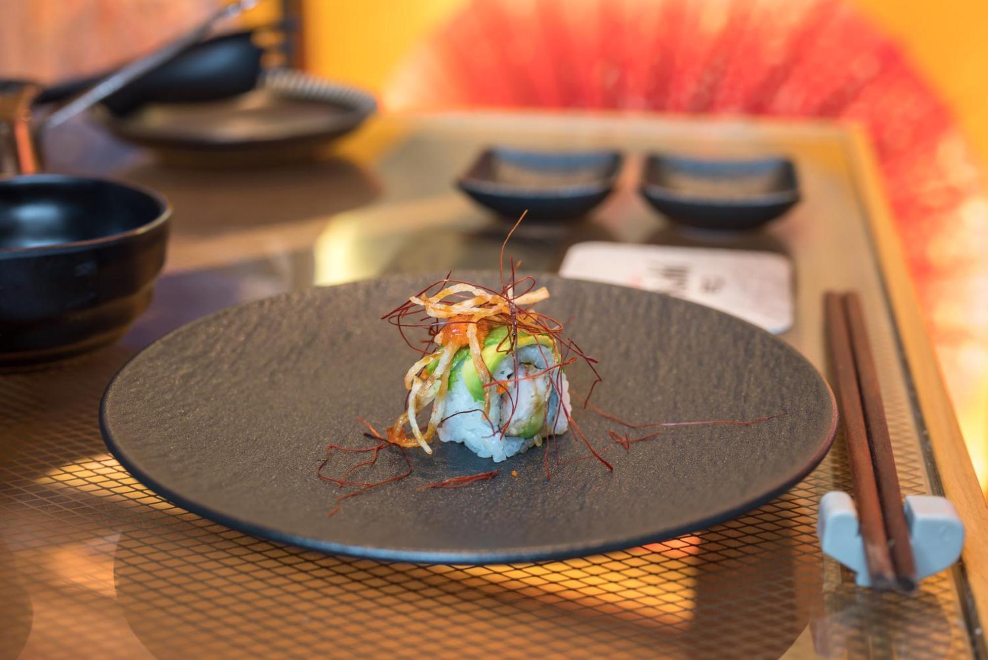Stella Di Mare Dubai Marina Hotel Esterno foto The photo shows a beautifully arranged plate of sushi presented on a black dish. The sushi appears to be topped with thinly sliced vegetables and garnished with what looks like fried or crispy strands, adding texture and color. There are chopsticks p