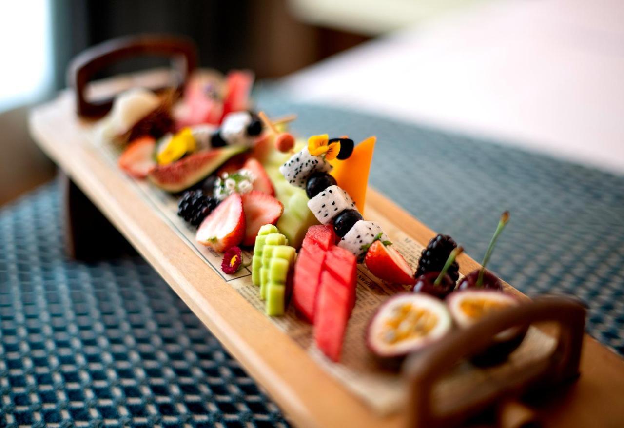 Stella Di Mare Dubai Marina Hotel Esterno foto The photo displays an artistic arrangement of assorted fruits and sushi on a wooden platter. The selection includes various types of sushi, which may be accompanied by colorful slices of fruits such as watermelon, strawberries, and possibly melons. T